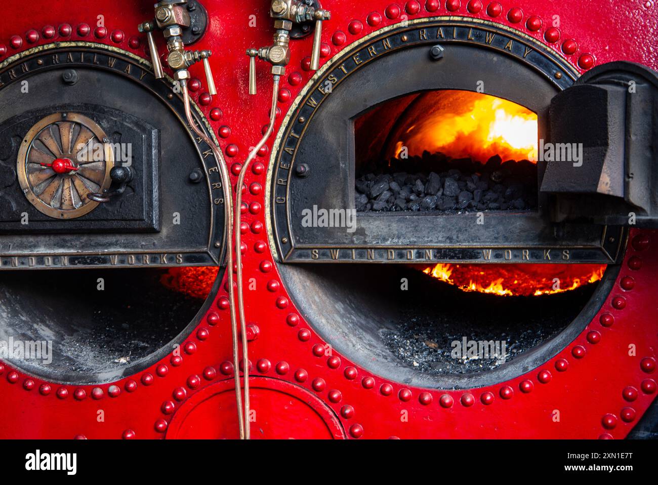 Vue rapprochée de la chaudière à vapeur du moteur Crofton Beam avec combustion de charbon à l'intérieur montrant les commandes métalliques complexes et la structure peinte en rouge. Banque D'Images