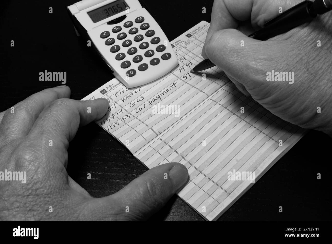 Homme faisant l'entrée dans le registre de chèque avec la calculatrice en noir et blanc. Banque D'Images
