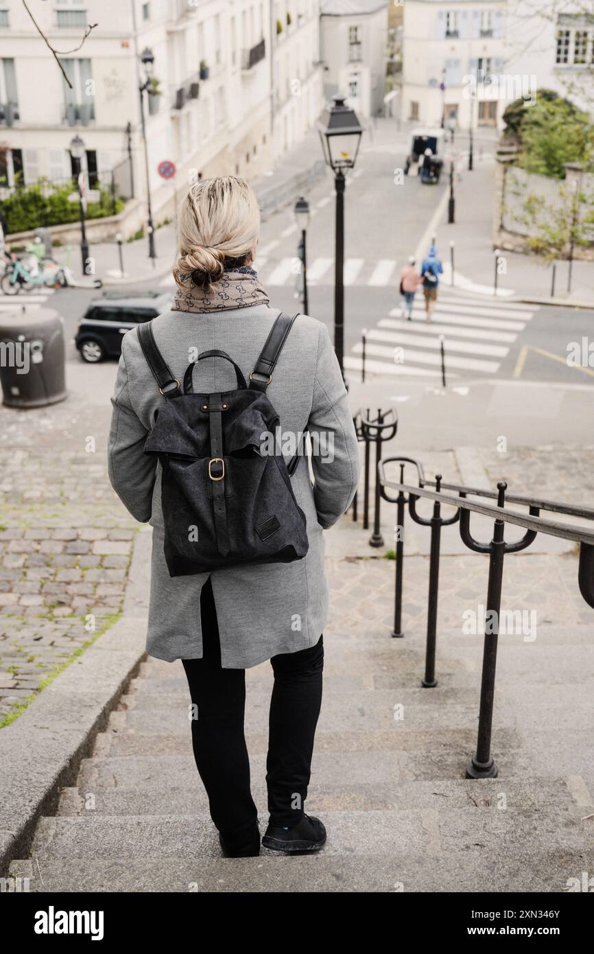 Une femme descend un escalier dans une rue calme de Paris, capturée par derrière. Paris, France Banque D'Images