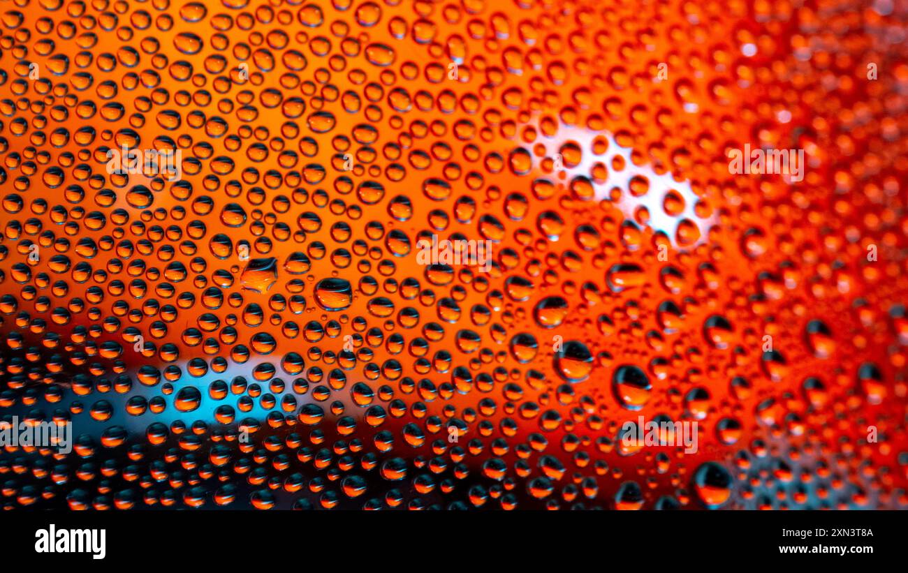 Macro de gouttes d'eau sur un dégradé de couleur rose/rouge/orange et jaune Banque D'Images