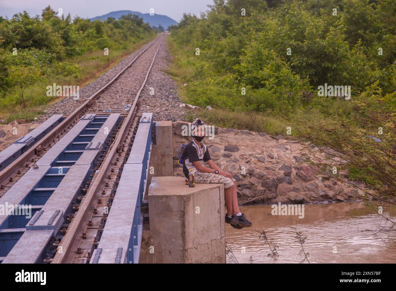 Un adolescent de race mixte, un touriste domestique, est assis sur un pont pour le train de bambou pendant COVID - 19. Province de Battambang, Cambodge. © Kraig Lieb Banque D'Images