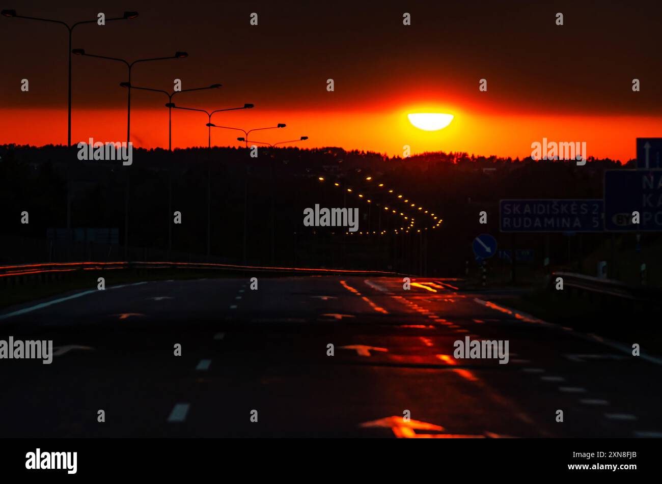 Asphalte Road et nuages colorés de ciel rouge au coucher du soleil Banque D'Images