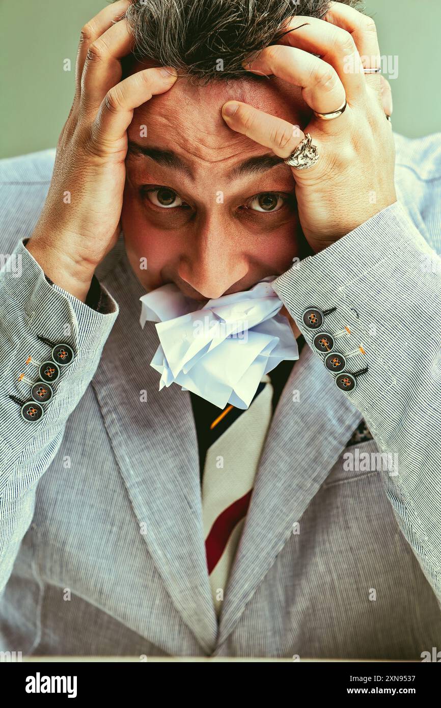 Homme d'affaires stressé bourrant la bouche avec du papier pour faire face à la pression et la responsabilité Banque D'Images