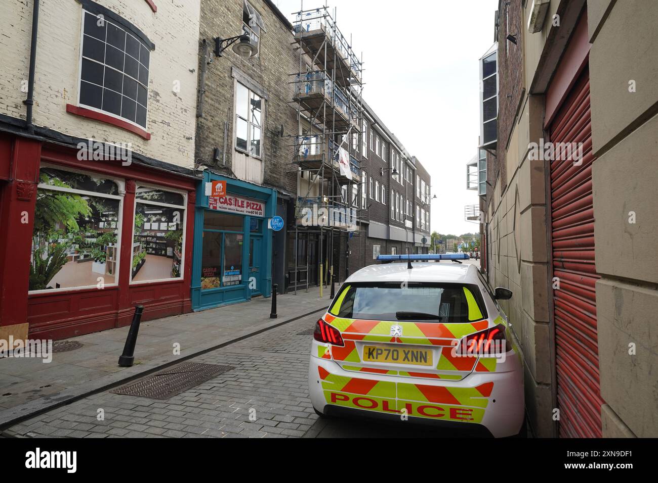 Une voiture de police garée devant un bâtiment désaffecté (à gauche) à Fore Bondgate, Bishop Auckland dans le comté de Durham, après qu'un squelette de bébé ait été trouvé sous les planches du plancher par des entrepreneurs travaillant sur une rénovation de propriété. Date de la photo : mercredi 31 juillet 2024. Banque D'Images