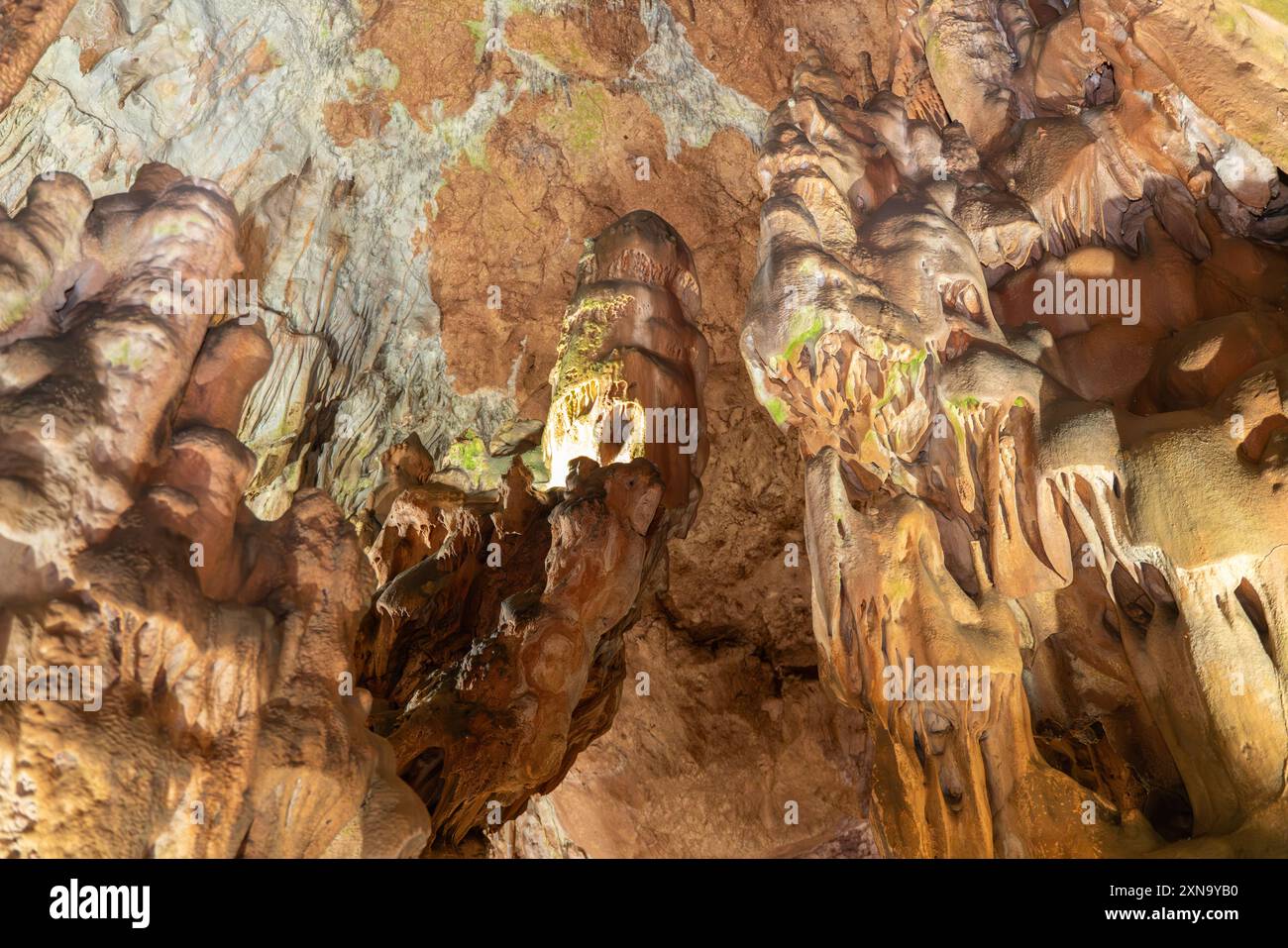 Une grotte avec beaucoup de formations rocheuses et un petit trou au milieu. La grotte est sombre et la lumière vient du trou. Banque D'Images