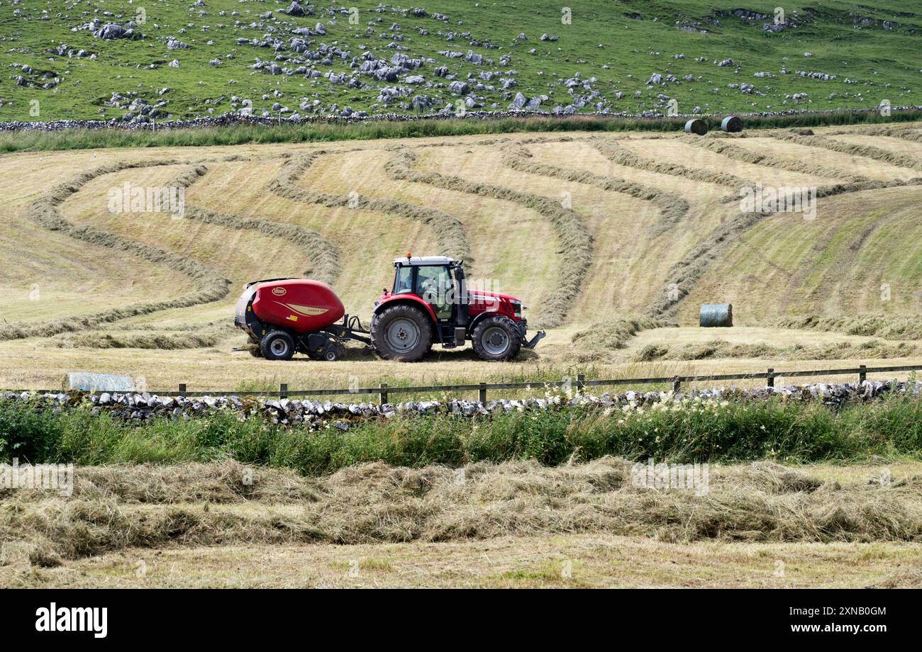 Fenaison près de Malham, Yorkshire Dales National Park, Royaume-Uni. Tracteur avec ramasseuse-presse produisant des balles rondes à partir d'herbe coupée. Banque D'Images