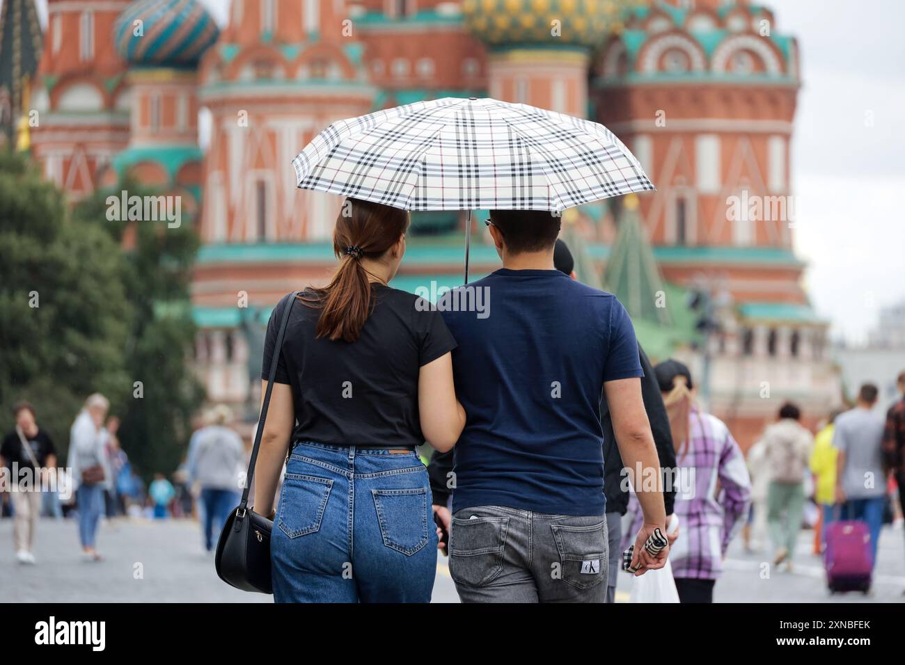Couple avec parapluie marchant sur la place Rouge sur fond de la cathédrale de Basile. Pluie en ville en été Banque D'Images