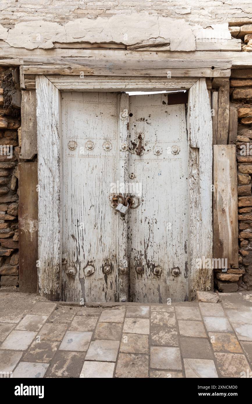 Ancienne porte en bois blanc dans un vieux mur de pierre, vue de face rapprochée. Photo verticale prise à Boukhara vieille ville, Ouzbékistan Banque D'Images