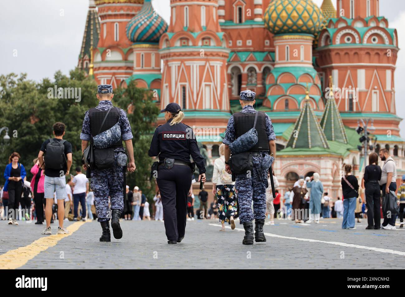 Soldats des forces militaires russes de la Garde nationale et femme de police marchant sur la place Rouge sur fond de la cathédrale Saint-Basile Banque D'Images