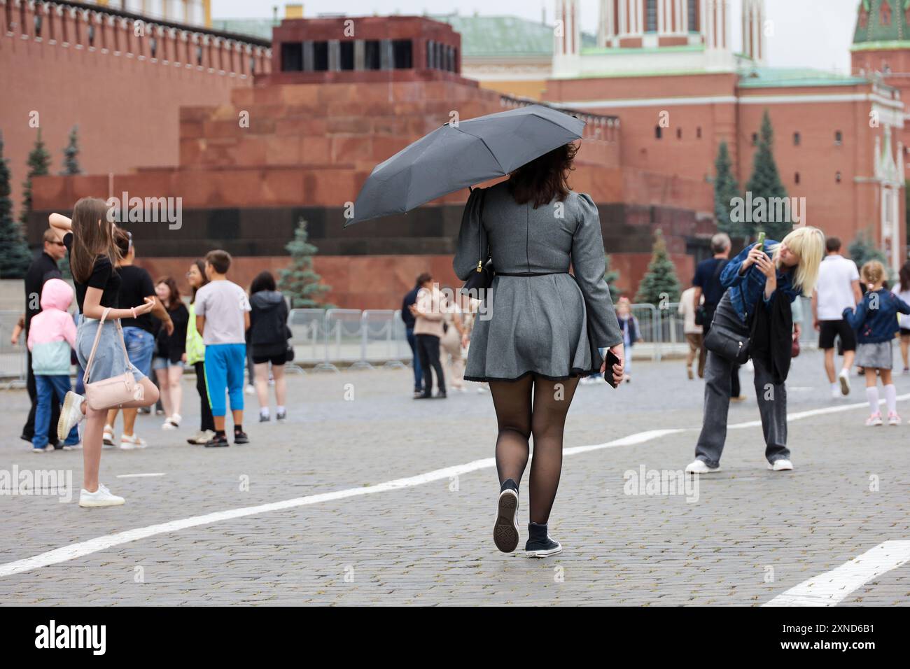Femme avec parapluie marchant sur la place Rouge. Pluie en ville en été Banque D'Images