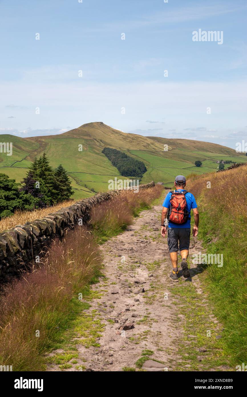 Homme marchant à dos le long d'une piste de campagne vers le Cheshire mini montagne Shutlingsloe dans le district de White Peak Angleterre Banque D'Images