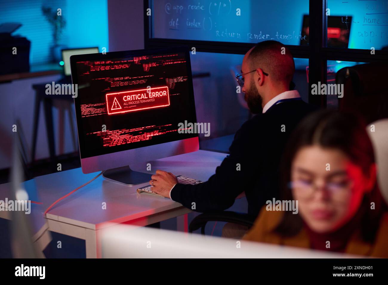 Bureau du département de cybersécurité avec message d'erreur critique sur l'écran d'ordinateur dans l'espace de copie des lumières au néon rouge Banque D'Images