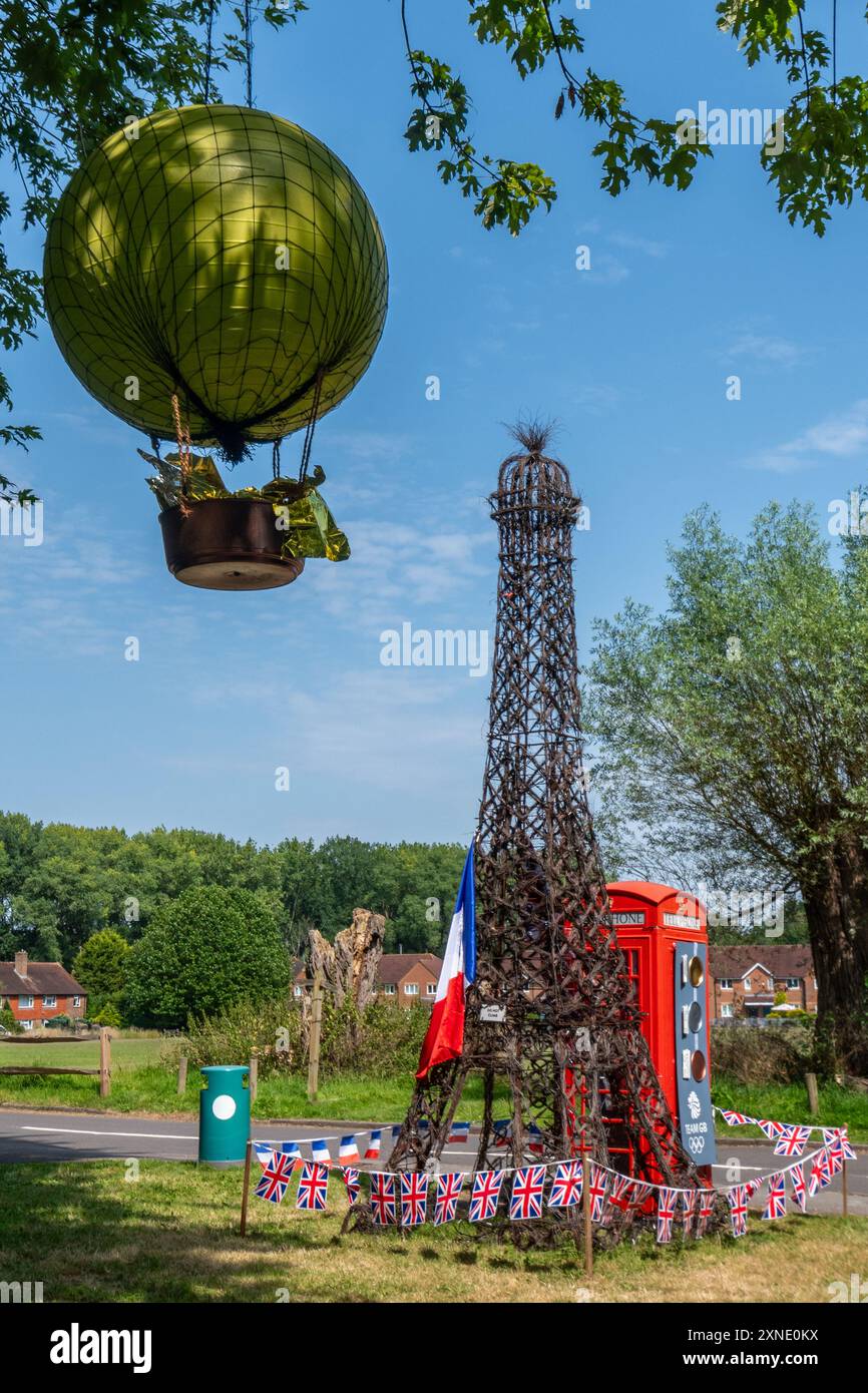 31 juillet 2024. Un coffret téléphonique rouge décoré pour célébrer les Jeux Olympiques de Paris. Les décorations des Jeux Olympiques comprennent un grand modèle de la Tour Eiffel à côté de la boîte téléphonique rouge traditionnelle avec le Chaudron olympique ou la flamme montgolfière dans un arbre voisin. Banque D'Images