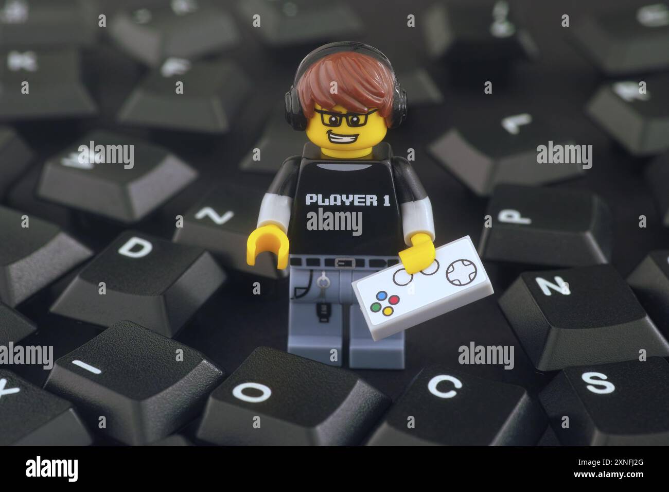 Tambov, Fédération de Russie - 31 juillet 2024 Une figurine Lego Video Game Guy avec manette de jeu debout dans une pile de touches noires du clavier d'ordinateur. Banque D'Images