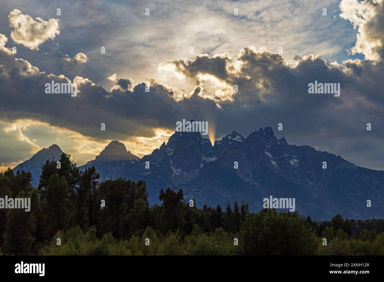 Le soleil couchant brille derrière Grand Teton Peak dans la chaîne de Teton du parc national de Grand Teton, comté de Teton, Wyoming, États-Unis. Banque D'Images