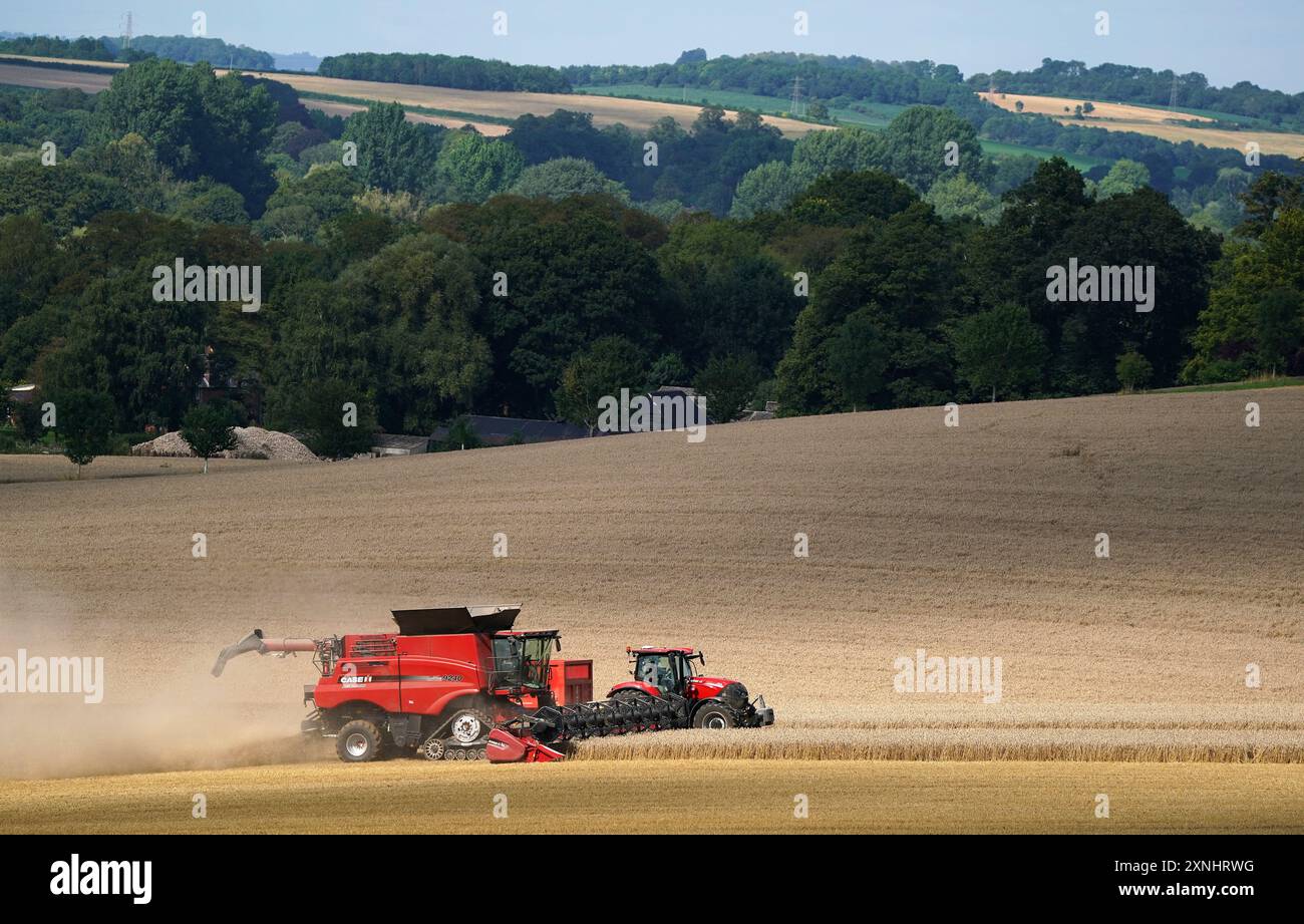 Photo du dossier datée du 24/8/2021 d'un tracteur se déplace aux côtés d'une moissonneuse-batteuse alors qu'elle décharge du grain pendant la récolte d'un champ près de Stockbridge dans le Hampshire. Le coût de la criminalité rurale au Royaume-Uni a dépassé les 50 millions de livres sterling estimés à mesure que les voleurs sont devenus plus organisés et déterminés, selon de nouveaux chiffres. Les coûts ont atteint 52 millions de livres sterling en 2023, contre 50 millions de livres sterling l'année précédente, selon le rapport de la NFU Mutual rural crime. Date d'émission : jeudi 1er août 2024. Banque D'Images