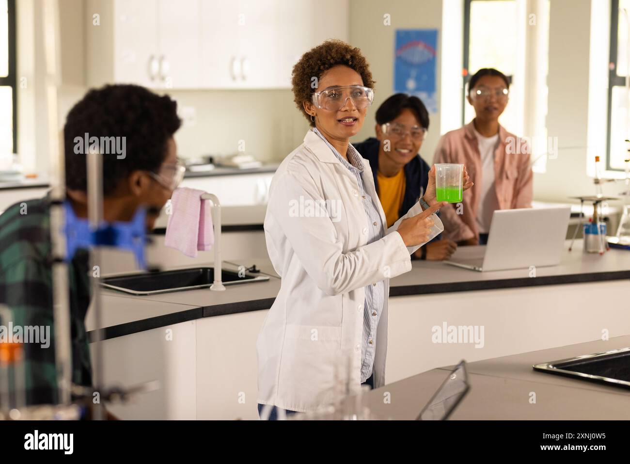 Dans le laboratoire du lycée, enseignant démontrant l'expérience avec bécher aux élèves Banque D'Images