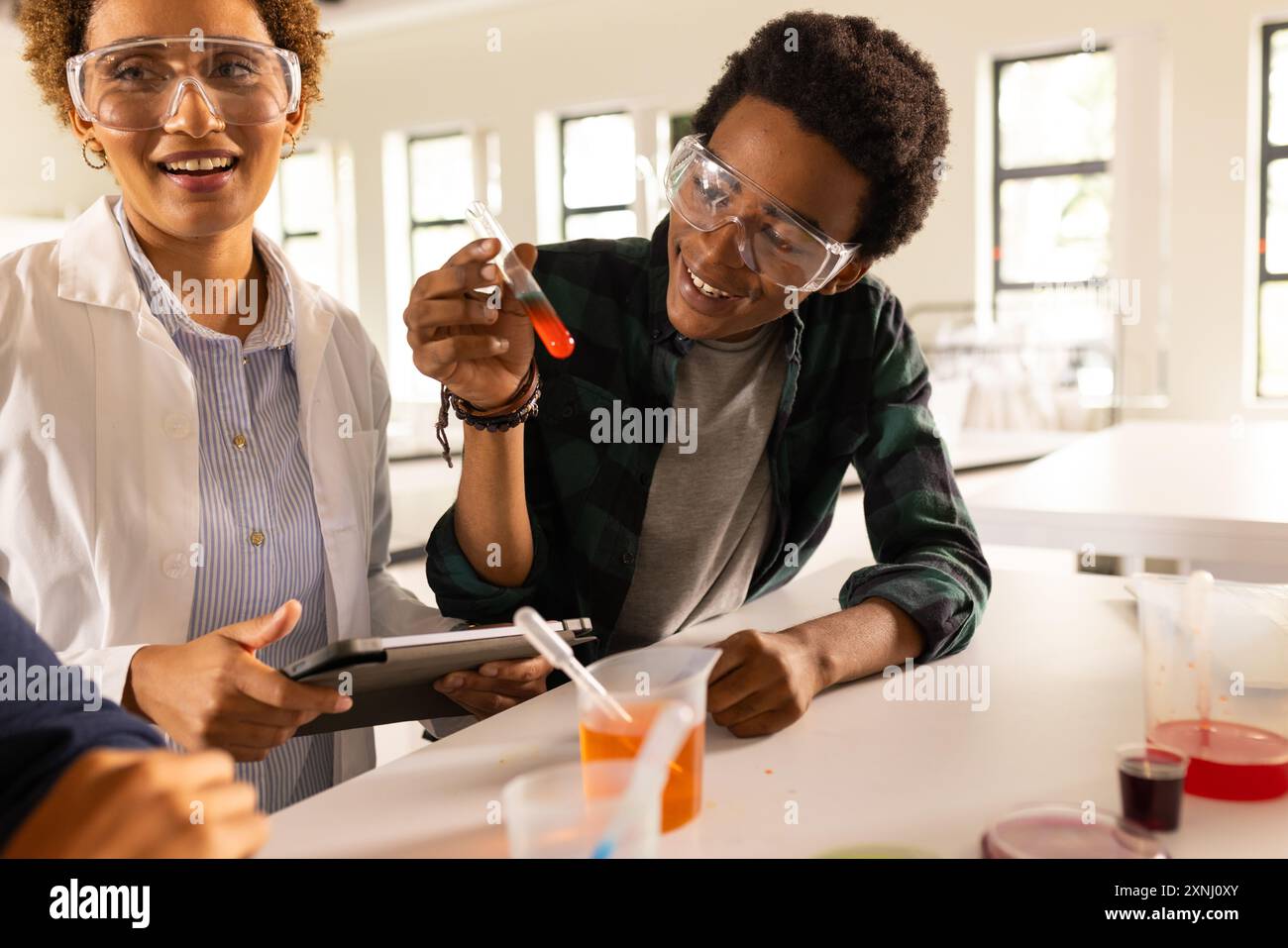 Au lycée, les élèves réalisent des expériences scientifiques avec des éprouvettes et des lunettes de sécurité Banque D'Images