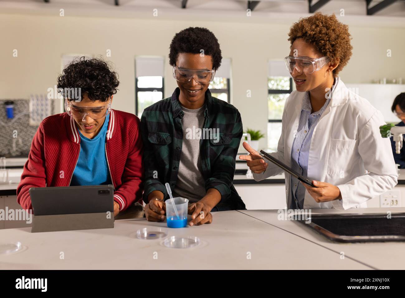 Mener une expérience scientifique avec tablette et bécher, adolescents dans la classe de lycée Banque D'Images