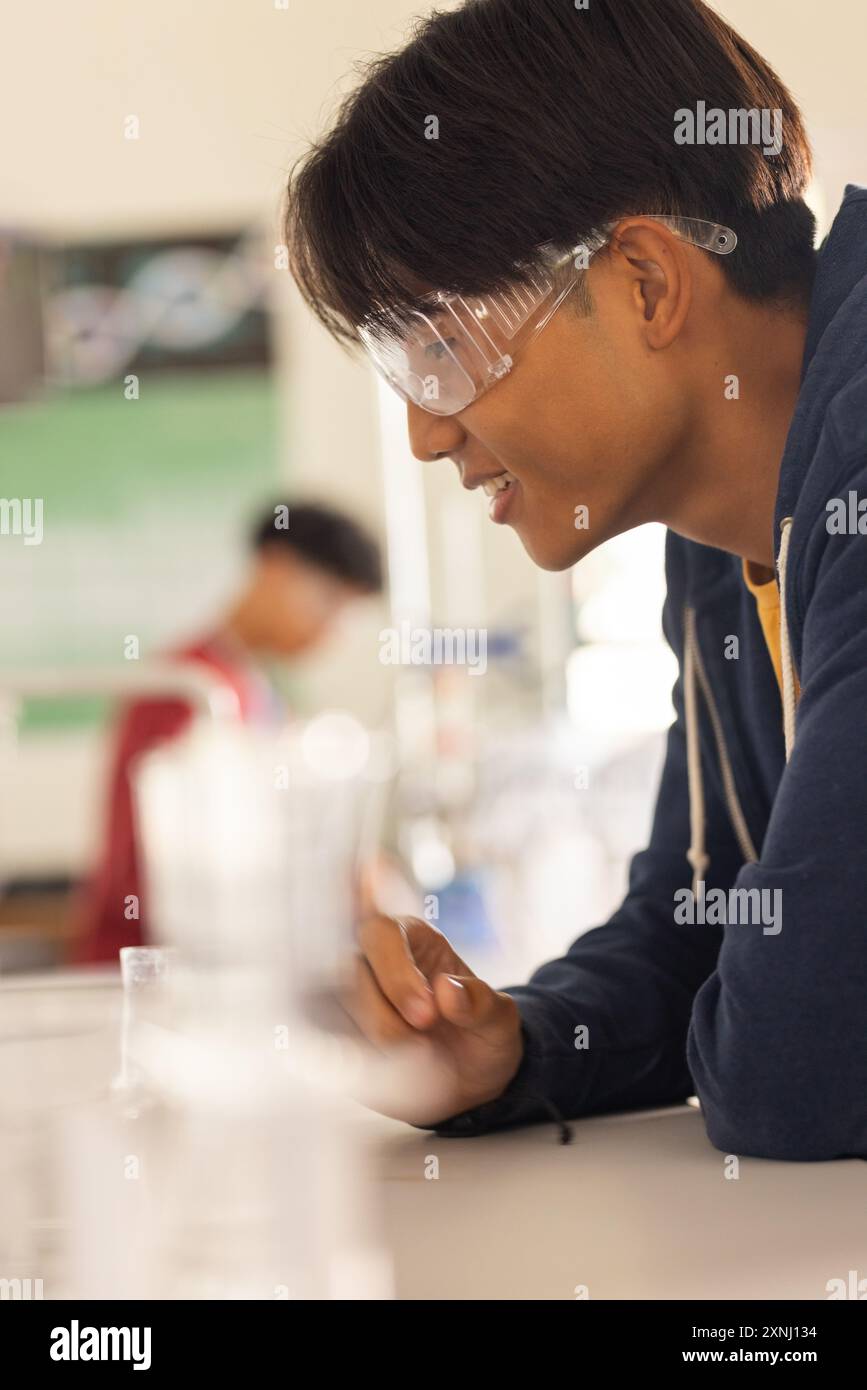Au lycée, adolescent portant des lunettes de sécurité menant des expériences en classe de sciences Banque D'Images