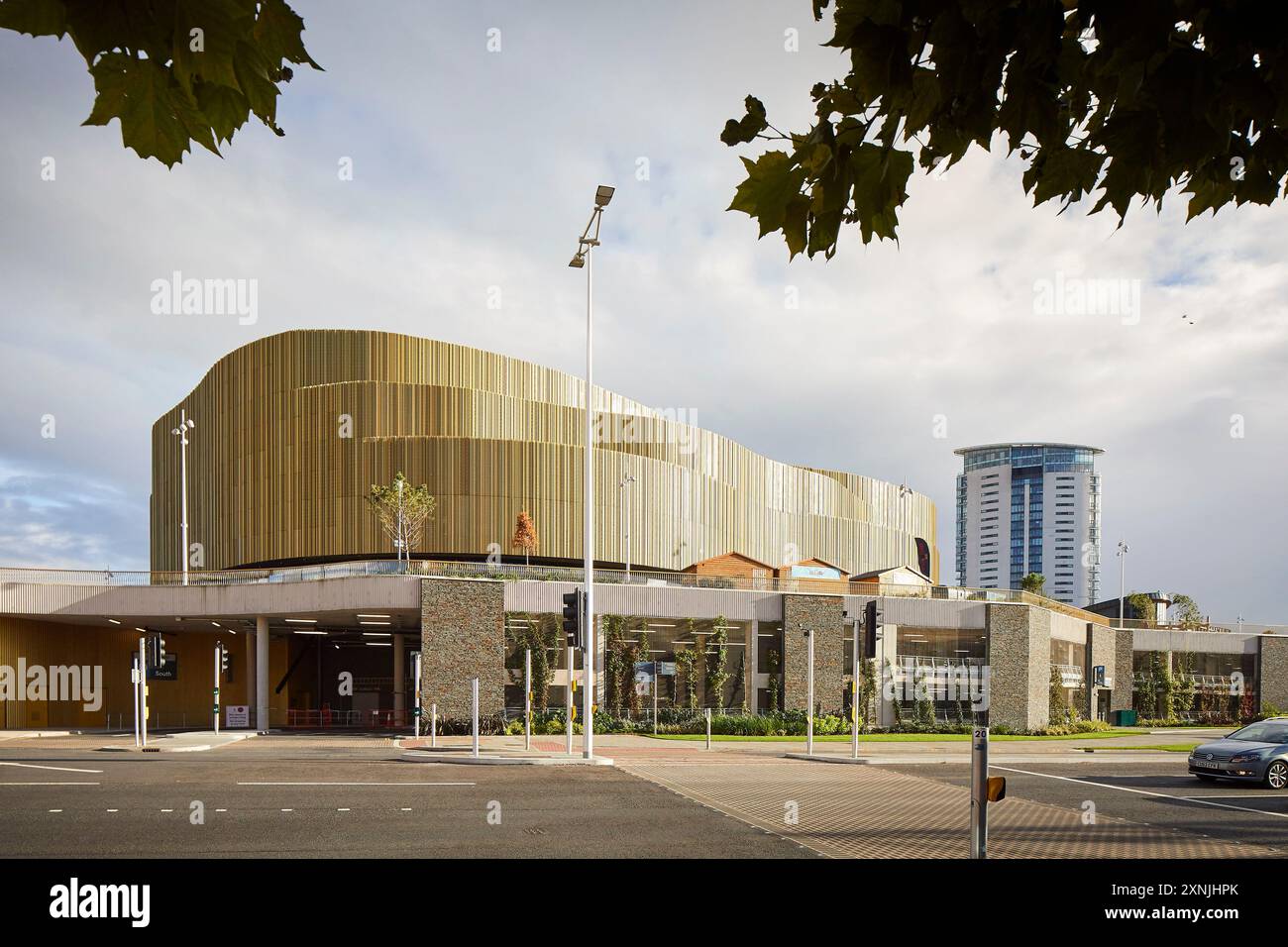 Domaine public paysager avec rue et arène curieux extérieur. Swansea Arena et Copr Bay Bridge, Swansea, Royaume-Uni. Architecte : acme, 2024. Banque D'Images