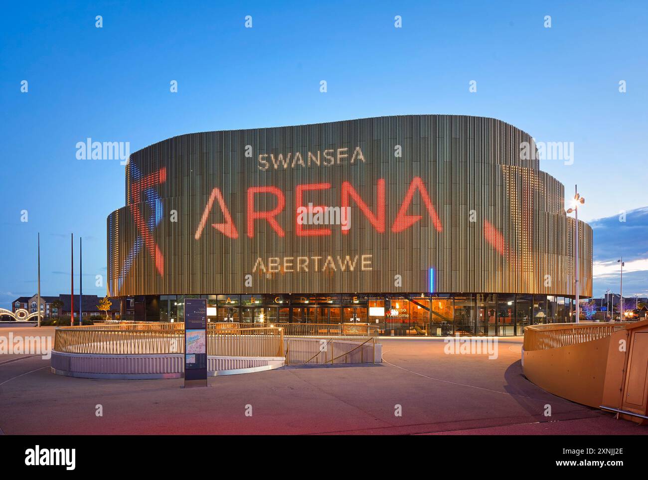 Façade extérieure avec éclairage LED au crépuscule. Swansea Arena et Copr Bay Bridge, Swansea, Royaume-Uni. Architecte : acme, 2024. Banque D'Images