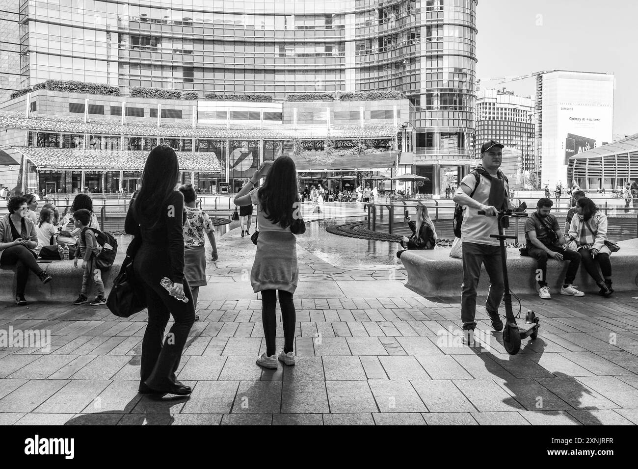 N&B Touristes à Piazza Gae Aulenti, une place moderne entourée de gratte-ciel célèbres dans le quartier d'Isola, Milan, Lombardie, Italie Banque D'Images