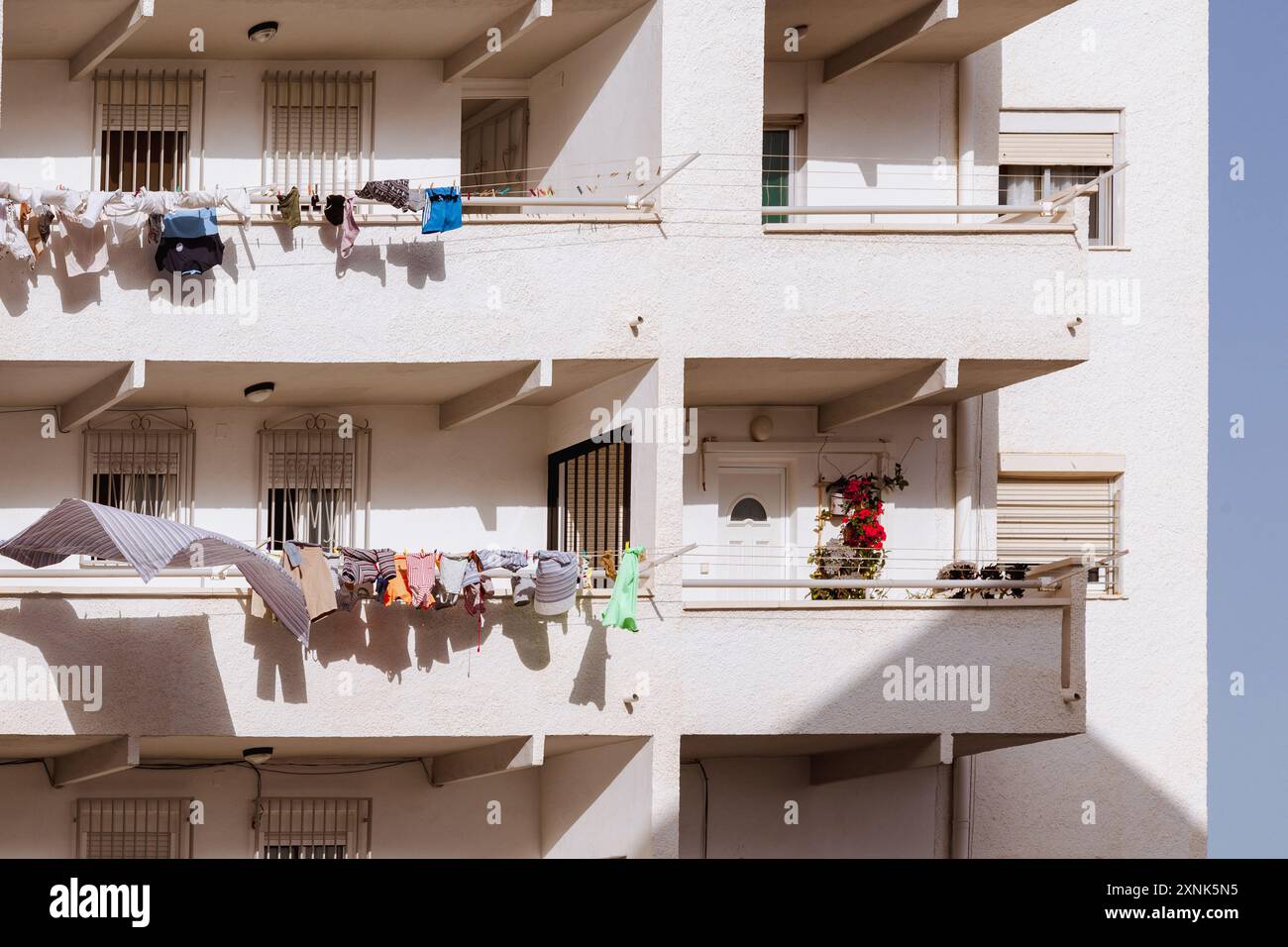 Une maison de pêcheur blanc à Villajoyosa avec un balcon avec linge suspendu et une plante en pot, capturant l'essence de la vie du village côtier. Banque D'Images