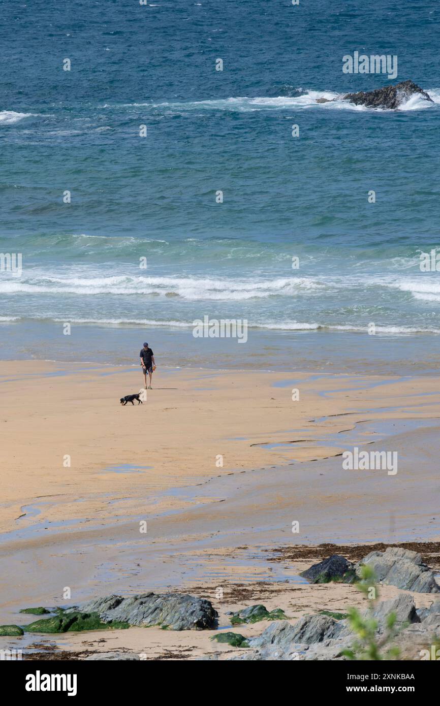 Un homme promenant son chien sur la plage à Polly Porth blague sur la côte de Newquay en Cornouailles au Royaume-Uni. Banque D'Images