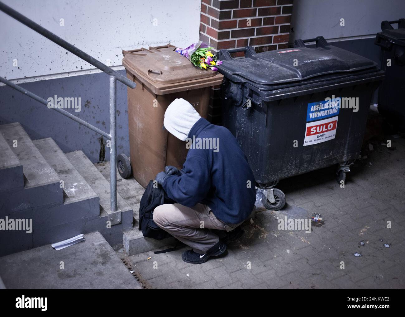 Un étudiant est montré plonger dans une benne à ordures, à la recherche de nourriture et de produits encore utilisables dans les poubelles de supermarché à Berlin, en Allemagne. Banque D'Images