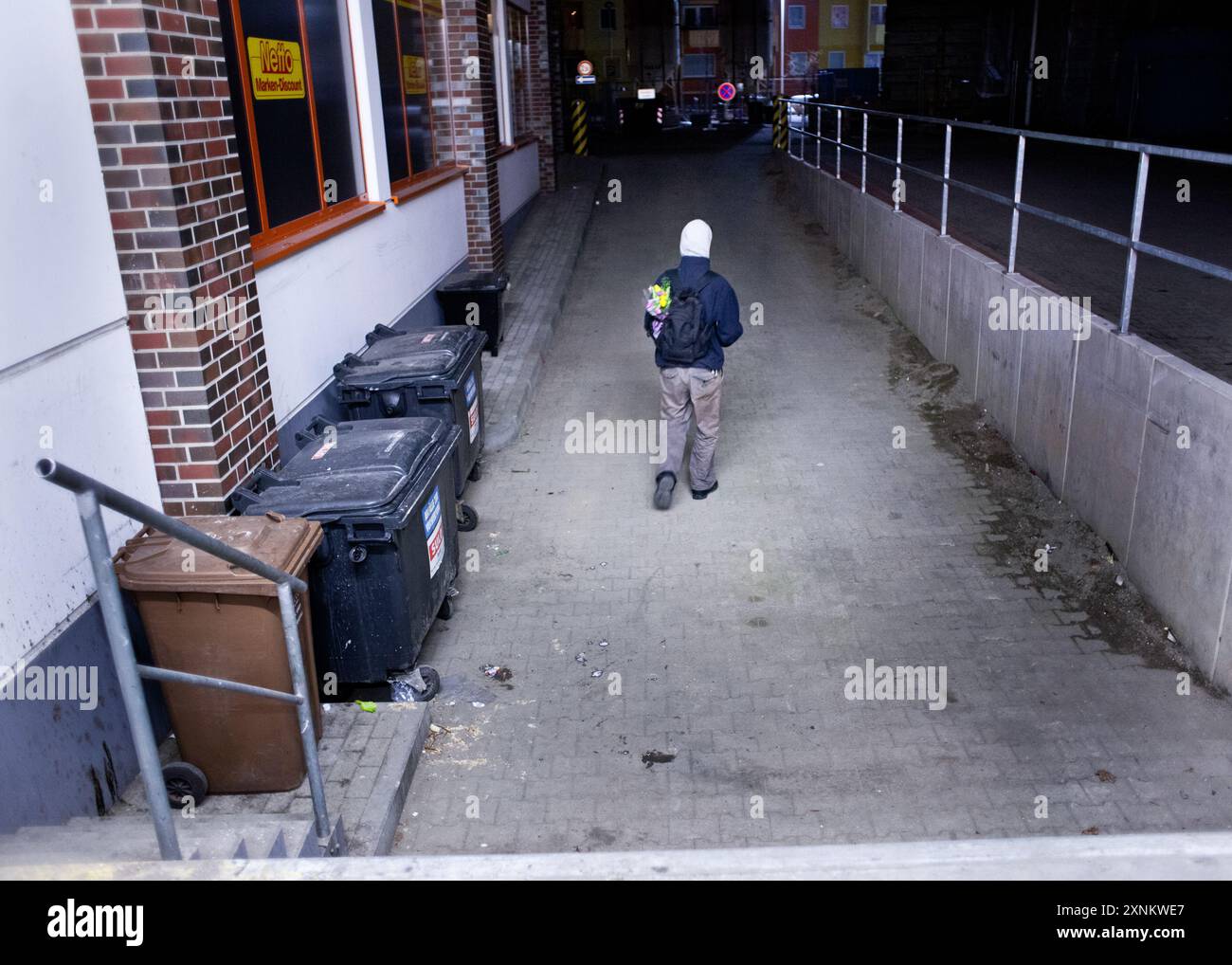 Un étudiant fouille dans les bennes de supermarché pour trouver des aliments et des produits utilisables à Berlin, en Allemagne. L'image capture l'acte de plongée dans une benne à ordures la nuit. Banque D'Images