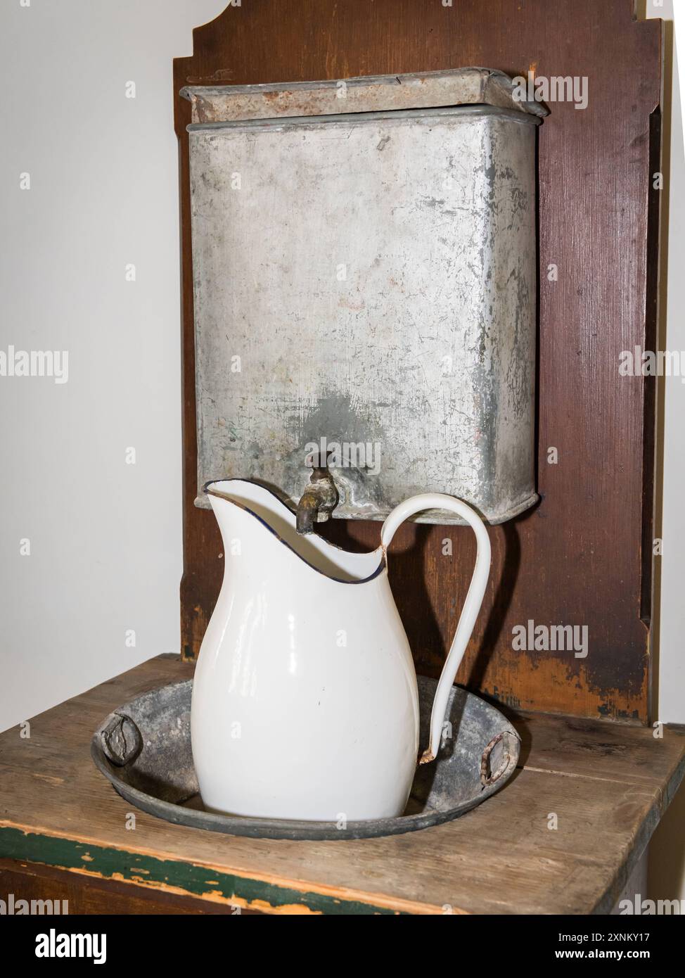 Une vieille cruche en métal blanc antique pour l'eau debout sur une table en bois Autriche Banque D'Images