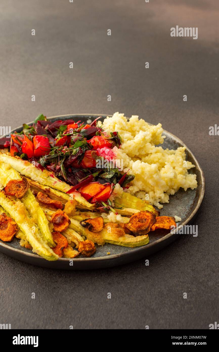 Dégustez un copieux petit déjeuner ou un déjeuner avec millet, courgettes cuites au four et carottes, accompagnés d'une salade fraîche de légumes et d'herbes de saison, pour un déliciou Banque D'Images