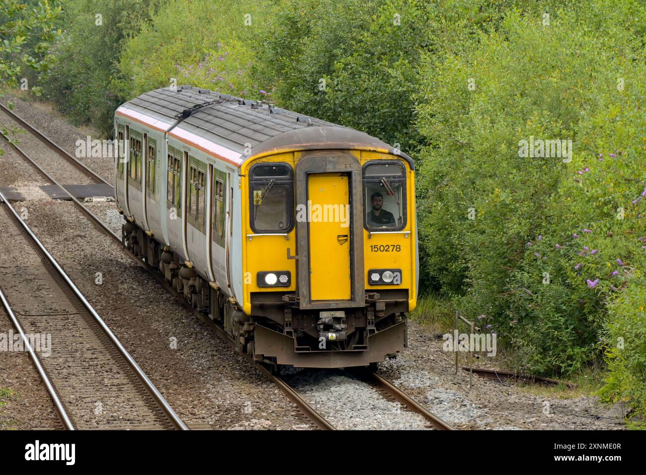 Pontyclun, pays de Galles, Royaume-Uni. - 31 juillet 2024 : train de banlieue diesel de classe 150 exploité par transport for Wales approchant de la gare du village Banque D'Images