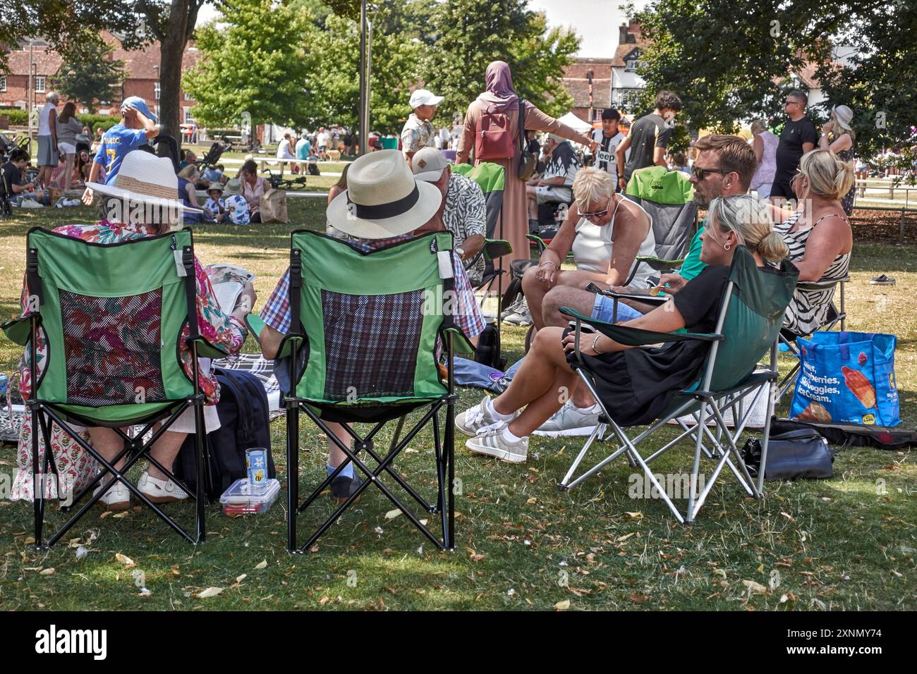 Les gens assis dans le parc sur des chaises pliantes appréciant le temps anglais de l'été. Angleterre Royaume-Uni Banque D'Images