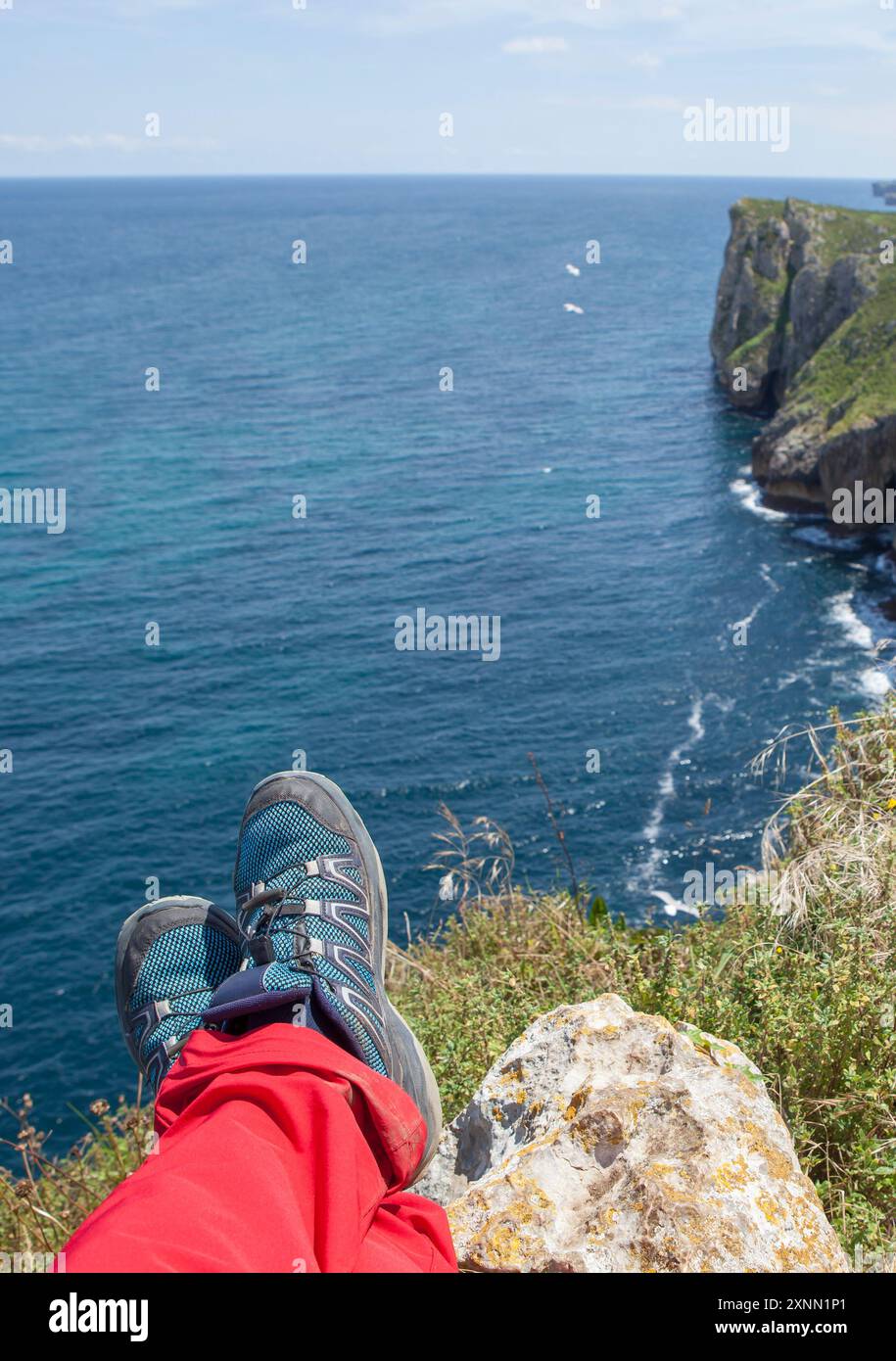 Trekker pieds reposant sur le bord des falaises de l'enfer, Ribadesella Asturies orientales, Espagne Banque D'Images