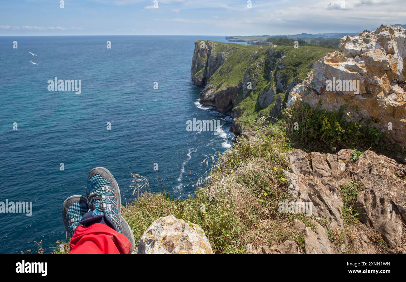Trekker pieds reposant sur le bord des falaises de l'enfer, Ribadesella Asturies orientales, Espagne Banque D'Images