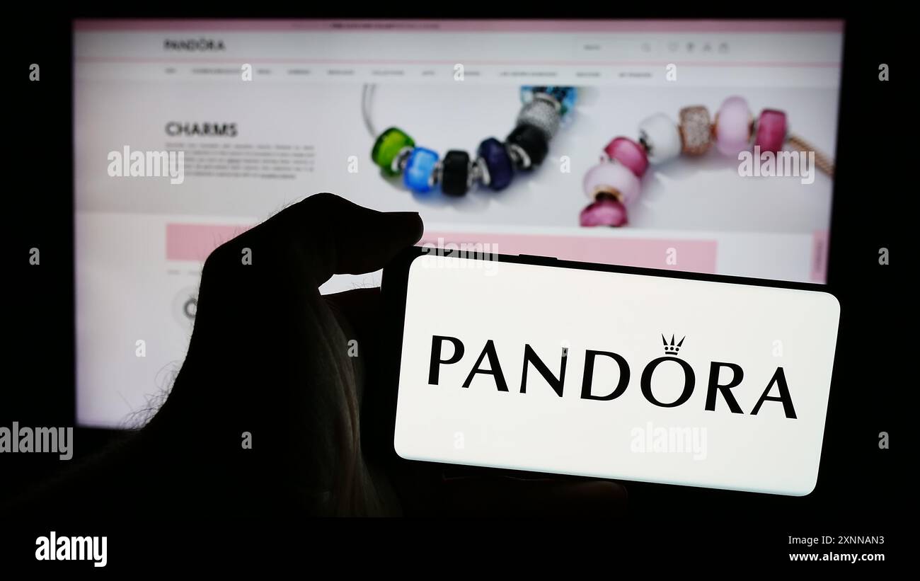 Personne tenant le smartphone avec le logo de la société danoise de bijoux Pandora COMME en face du site Web. Concentrez-vous sur l'affichage du téléphone. Banque D'Images