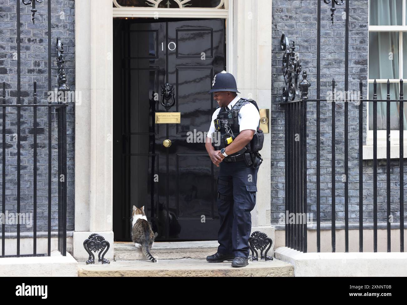 Larry le receveur de souris résident No.10 attendant d'être laissé entrer par British bobby sur Downing Street, Westminster, Londres, Royaume-Uni Banque D'Images