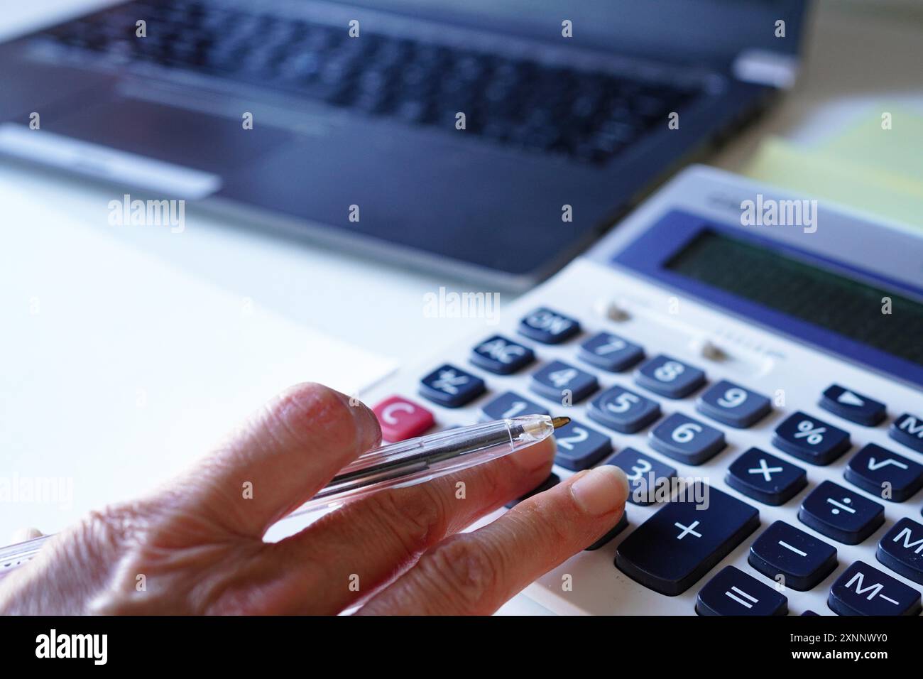 La main d'une consultante plus âgée faisant des calculs sur une calculatrice dans son bureau Banque D'Images