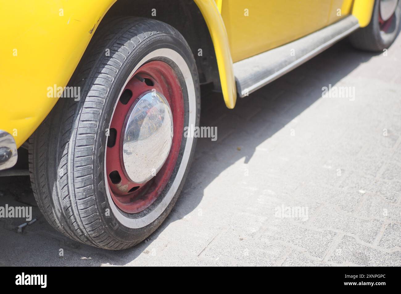 Une voiture jaune vintage classique avec un accent rouge frappant sur le design de ses roues Banque D'Images