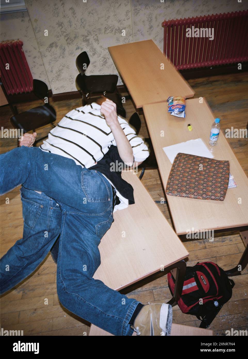 Une violente bagarre éclate dans une salle de classe, provoquant le chaos avec des bureaux renversés et des étudiants se livrant à des bagarres physiques. L'image capture l'intense Banque D'Images