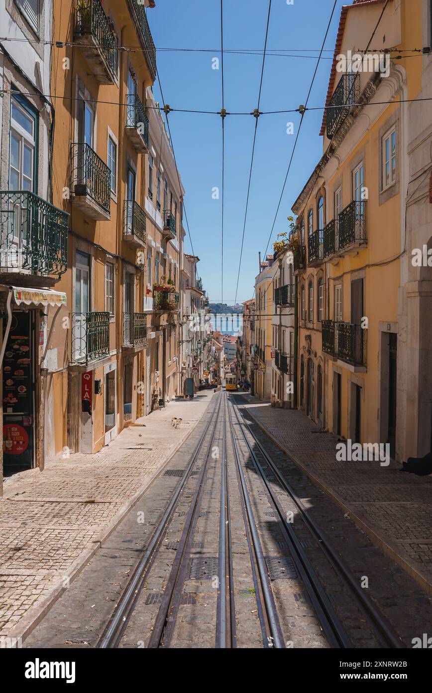 Rue étroite escarpée avec des pistes de tramway emblématiques à Lisbonne, Portugal Banque D'Images