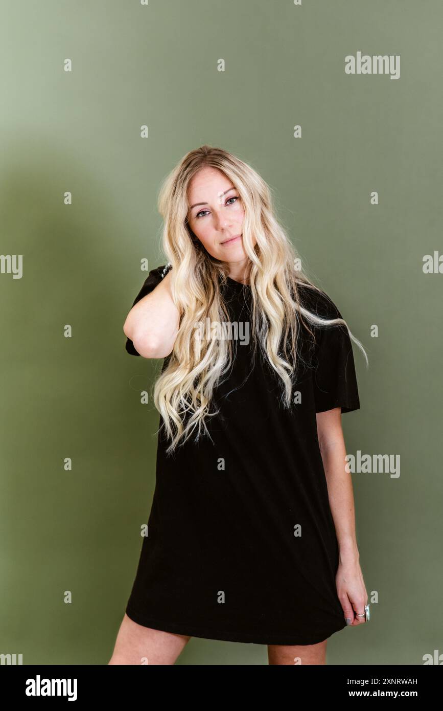 Femme blonde à la mode dans une robe de t-shirt noir posant contre Banque D'Images