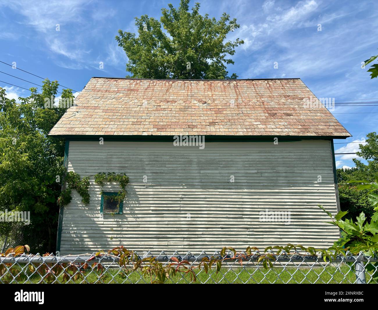 Hangar blanc altéré entouré de verdure sous le ciel bleu dans le Vermont Banque D'Images