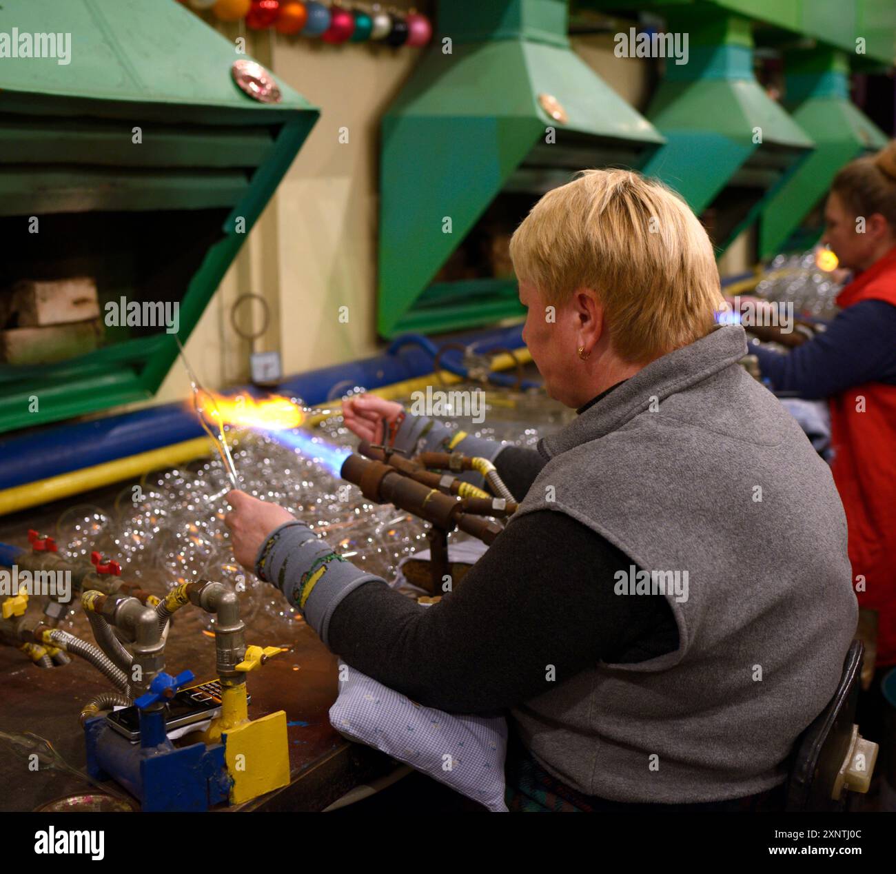 Femme souffleur de verre soufflant l'ébauche de verre faisant boule de décoration de Noël, hall de production d'une usine de jouets. 10 décembre 2018. Klavdiive, Ukraine Banque D'Images