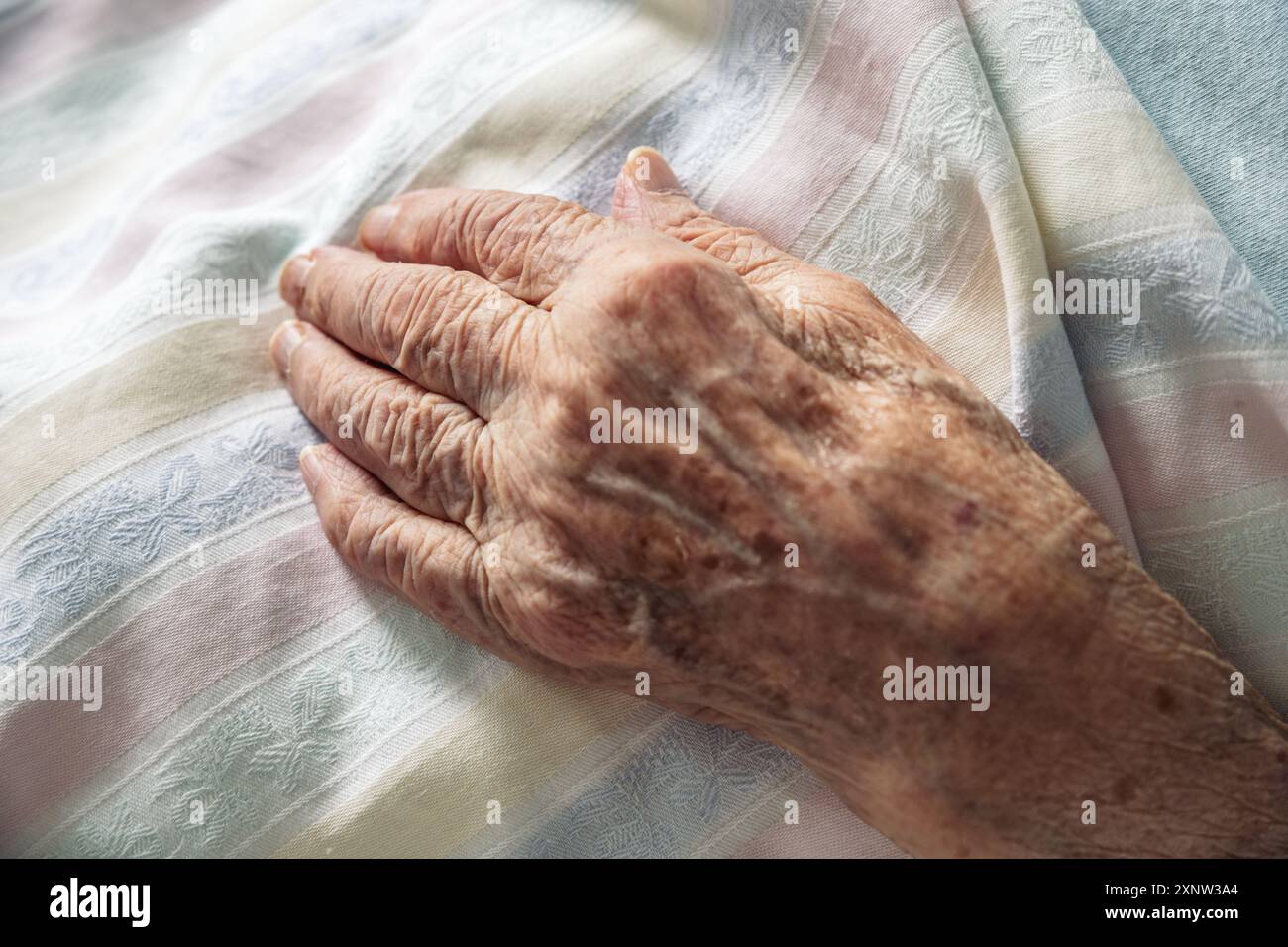 Main tordue d'une vieille femme âgée de 100 ans reposant paisiblement sur la literie de l'hôpital. Concept de vie, vieillissement, santé, maladie, dignité, compassion, mourir ... Banque D'Images