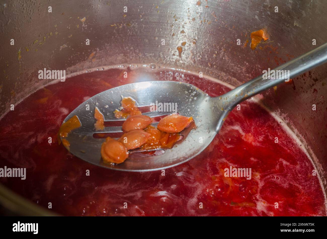 Dénoyautage des prunes à l'aide d'une cuillère fendue pendant la procédure de confiture Banque D'Images