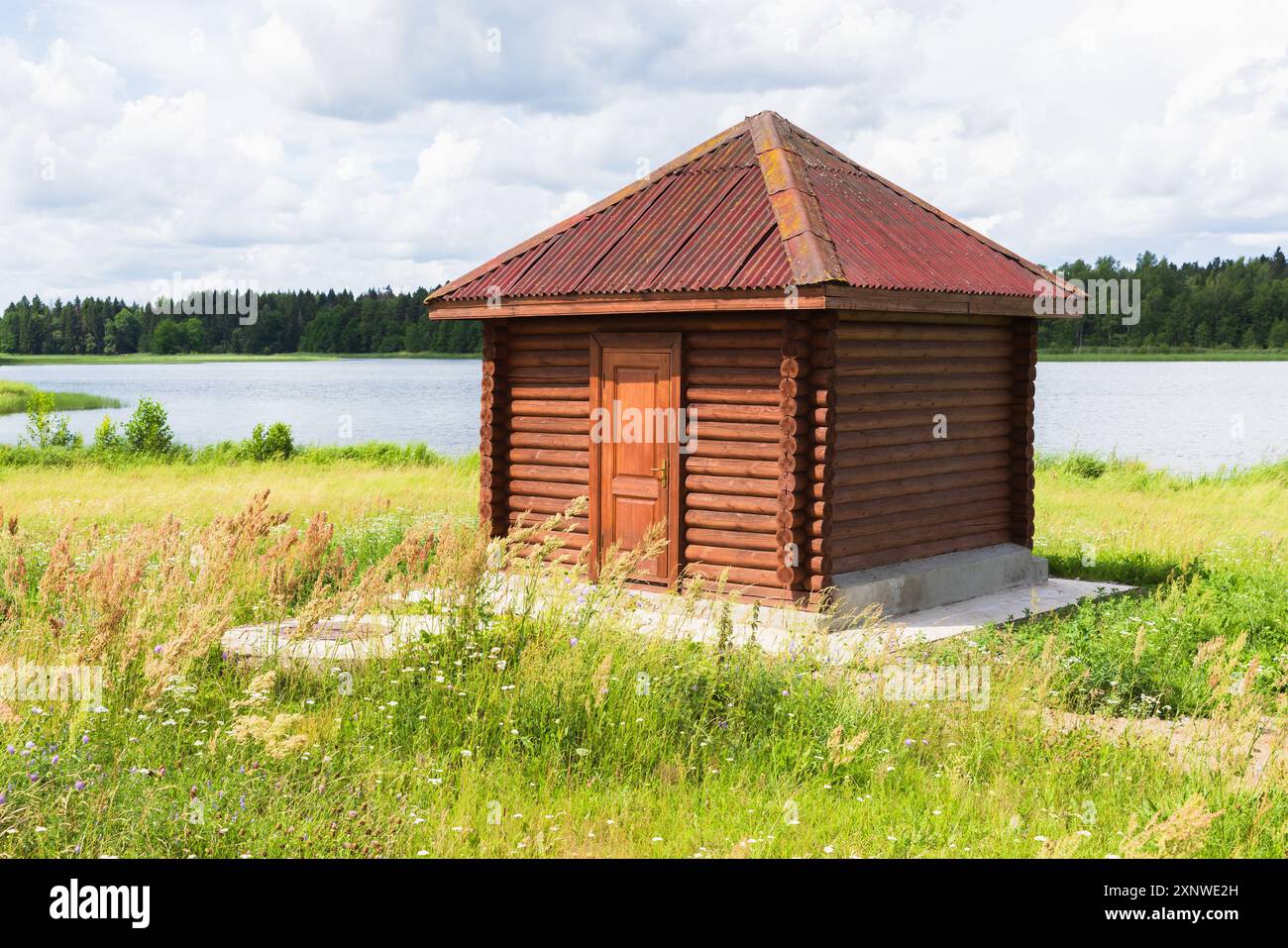 Petite cabane en bois se dresse sur la côte du lac par une journée ensoleillée dummer. Bâtiment de service sur la côte du lac Banque D'Images