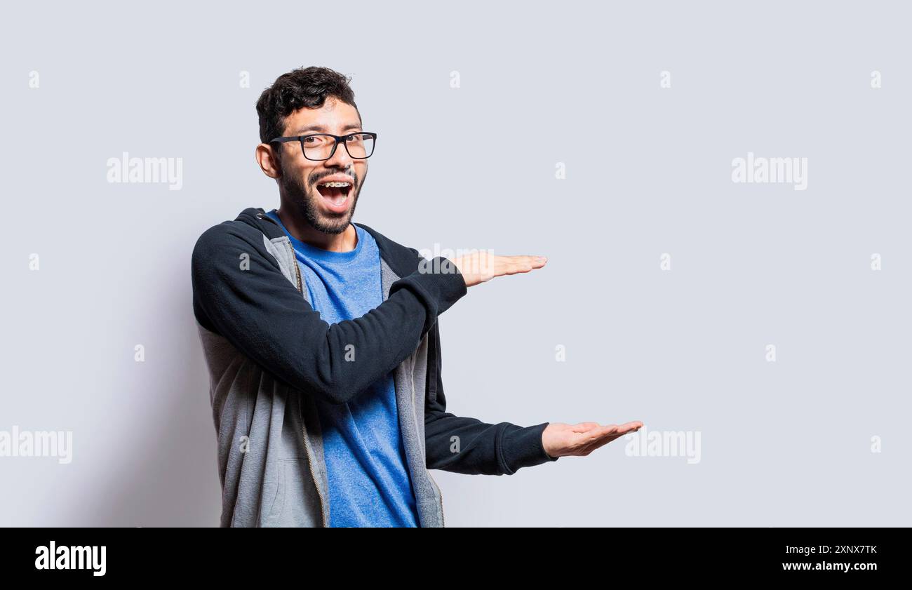 Personne souriante montrant un objet avec ses paumes, homme surpris montrant quelque chose avec ses paumes sur fond isolé, les gens présentant quelque chose Banque D'Images